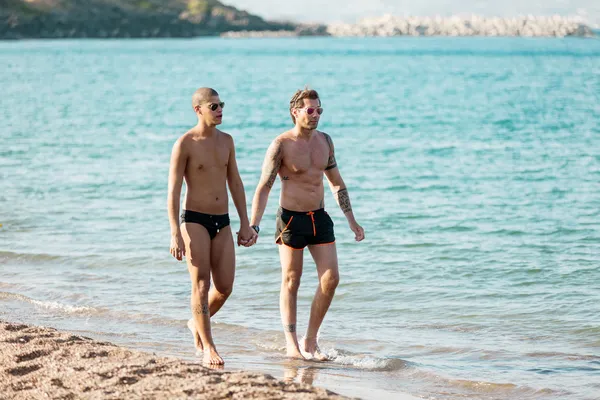 Gay casal são segurando mão enquanto andando ao longo o praia — Fotografia de Stock