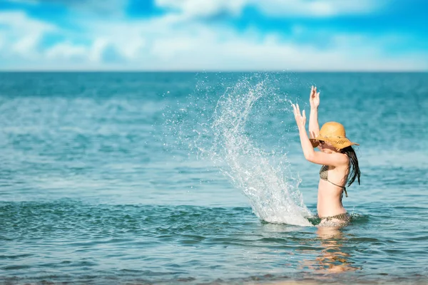 Mulher está brincando com salpicos de água na praia — Fotografia de Stock