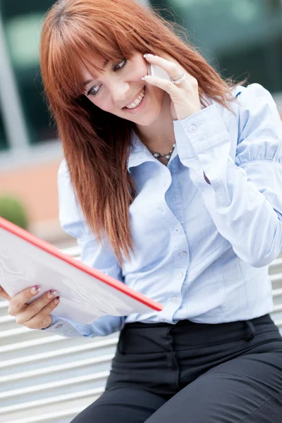 Red hair Businesswoman is sitting on a metal bench and phoning — Stock Photo, Image