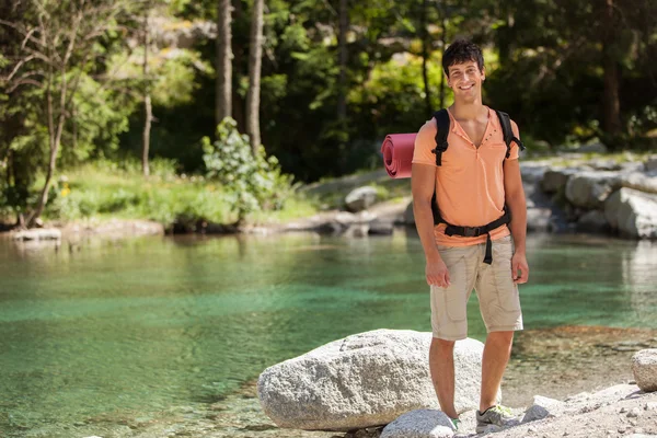 Uomo con attrezzatura da trekking in piedi accanto a un lago — Foto Stock