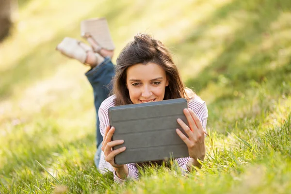 Jolie femme brune avec un sourire magnifique allongé sur une herbe — Photo