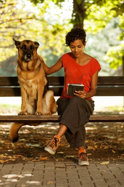 Mujer en un banco con tableta digital y perro — Foto de Stock