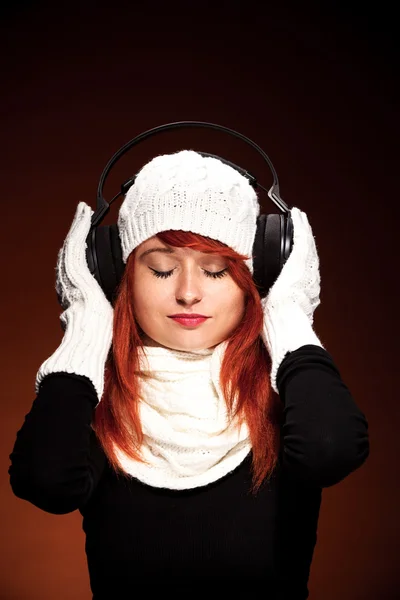 Mulher de cabelo vermelho com roupa de inverno ouvindo música — Fotografia de Stock