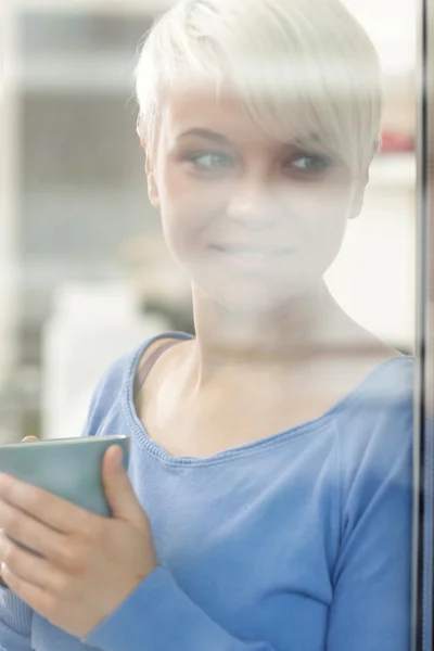 Atractiva mujer disfrutando de su café detrás de una ventana —  Fotos de Stock