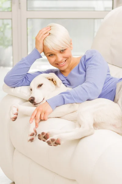 Mulher loira está brincando com seu cão — Fotografia de Stock
