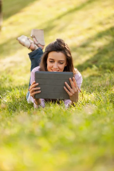 Jolie femme brune avec un sourire magnifique allongé sur un champ d'herbe — Photo