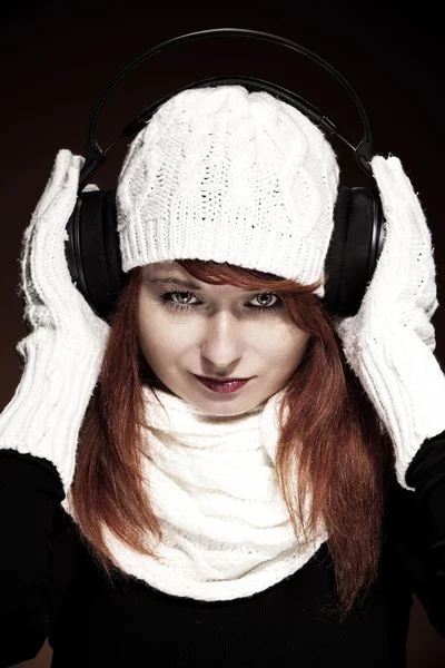 Frau mit roten Haaren und winterlichem Outfit hört Musik — Stockfoto