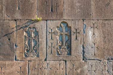 Eski bir ortaçağ Ermeni kilisesinin duvarı. Arka planda haçlar ve diğer Hristiyan özellikleri var.