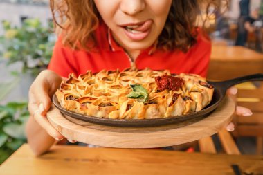 Lokantada lezzetli manti ya da börek yemeden önce dudaklarını yalayan bir kadın. Geleneksel Doğu ve Türk mutfağı