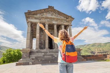 Ermenistan 'daki Garni Tapınağı' nda sırt çantalı mutlu bir kadın gezgin veya öğrenci - UNESCO 'da listelenen antik bir anıt