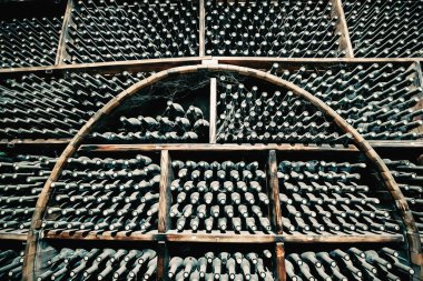 Şarap mahzeninde tozla kaplanmış yaşlanan alkol şişeleriyle dolu raflar..