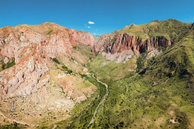 Kırmızı jeolojik kayalarla dolu bir nehir vadisindeki destansı bir vadide hava aracı görüntüsü. Ermenistan 'daki Noravank Manastırı' nda vuruldu.