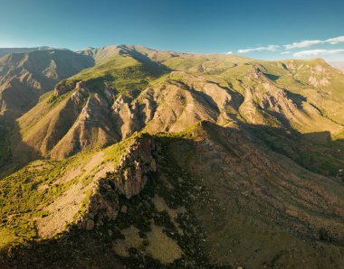 Dağlardaki kayalıkların ve kayaların havadan görünüşü batan güneşin ışınlarıyla aydınlatılan şaşırtıcı bir şablon oluşturur. Jeolojik çıkıntılar ve kir kavramı