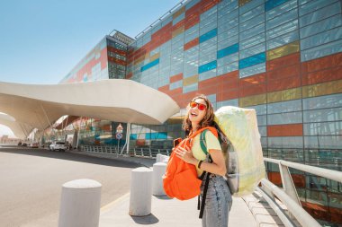 İki büyük sırt çantalı komik bir kadın. Plastik bantla havaalanına gitmek için acele ediyor.