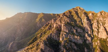 Yükselen güneşin ışınlarıyla aydınlatılan şaşırtıcı bir şablon oluşturan kayalıkların ve kayaların havadaki çarpıcı görüntüsü. Işık ve gölgenin oyunu