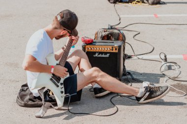 21 Ağustos 2021, Ufa, Rusya: Bir sokak gitaristi sahneye çıkmadan önce Marshall gitar amfisini akort ediyor. Ses kontrolü ve ekipman