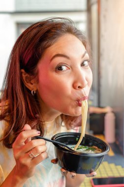 Fast food kafede Kore ramen çorbası içen Asyalı bir kadın.