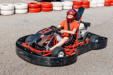 Go-kart kullanan mutlu genç çocuk kartodrom etrafında daireler çiziyor. Bir çocuk için hobiler ve ekstrem sporlar ve bir hayalin gerçekleştirilmesi