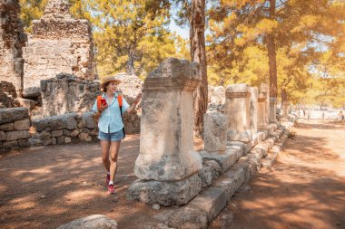 Kadın gezgin, Yunanistan 'ın tuhaf Phaselis kentinin antik harabelerinde yürüyor. Tarihi görüntüler ve arkeoloji