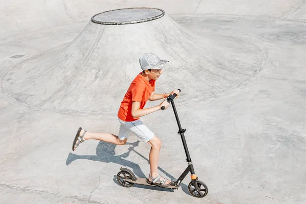10代の男の子が街の極端な公園のランプでスクーターに乗っています ヘルメットと保護なしで 危険なスポーツの概念 — ストック写真