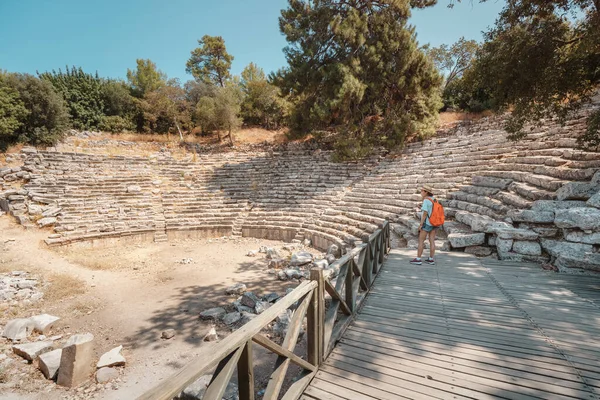 一人の観光客の少女は 現在のトルコの古代都市ファセリスの古代ギリシャの円形劇場の遺跡を探索します — ストック写真