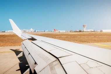 Bir yolcu uçağının kanadı ve havaalanındaki kontrol kulesi. Seyahat ve hava taşımacılığı kavramı