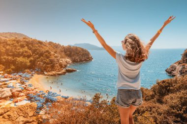 Kolları açık, mutlu bir kadın... Akdeniz kıyısındaki sahil manzarasının tadını çıkarıyor.