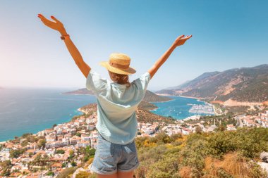 Kolları açık olan mutlu kadın, Türkiye 'nin Akdeniz kıyısındaki Kas tatil beldesinin manzarasının keyfini çıkarıyor.
