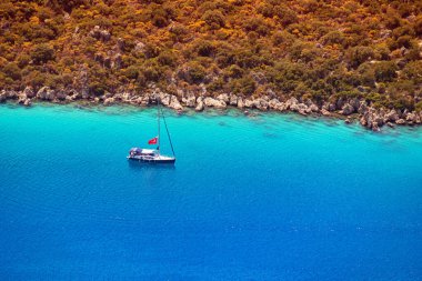 Akdeniz 'in pitoresk bir cennetinde, direğinde Türk bayrağı olan küçük bir yatın havadan görünüşü..