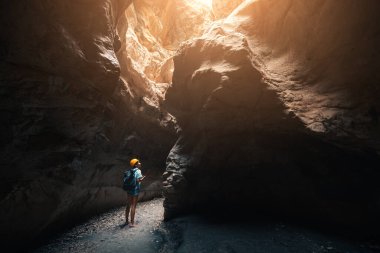 Kaskı ve sırt çantasıyla dağlarda derin ve karanlık bir vadide yürüyüş yapan biri. Yeni deneyim ve açık hava eğlencesi.