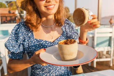 Genç bir kadın terasta restoranda Testi kebap yiyor. Sürahiyi kırdıktan sonra servis edilen, kilden bir tencerede pişirilmiş otantik bir Türk eti..