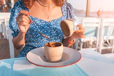 Genç bir kadın terasta restoranda Testi kebap yiyor. Sürahiyi kırdıktan sonra servis edilen, kilden bir tencerede pişirilmiş otantik bir Türk eti..