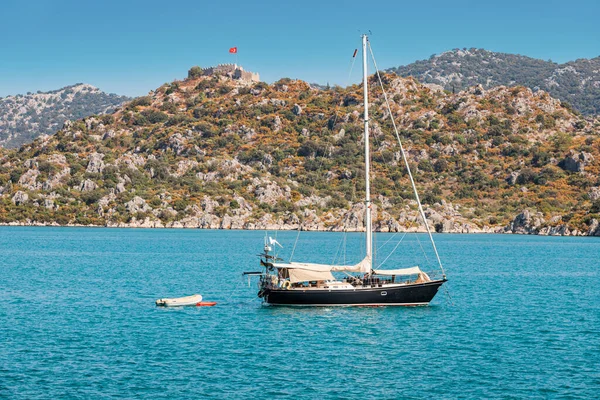 Türkiye 'nin batık antik Kekova kenti yakınlarında Türk bayrağıyla yüksek bir kayanın üzerindeki Simena şatosunun arka planına doğru yelken açıyor.