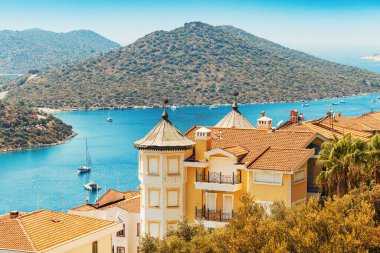 Akdeniz 'in dik yamacındaki bir tatil köyünde kırmızı çatıları olan evler ve villalar. Gayrimenkul ve kentsel kalkınma kavramı