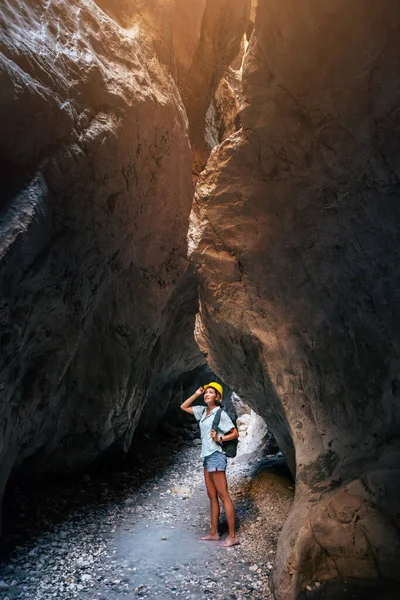 Happy alone woman wearing helmet for safety is engaged in active canyoning and hiking along the Saklikent Gorge in Turkey. New experience and outdoor leisure recreation