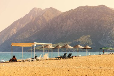 29 Ağustos 2021, Cirali, Türkiye: Tatilciler, Türkiye 'nin Taurus Dağları manzaralı Cirali plajında güneşleniyor ve yüzüyorlar