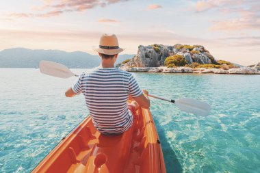 Türkiye 'nin Kekova kentindeki antik bir lahit ve Lycian mezarının yanında kano ile gezen mutlu adam görülüyor. Sahilde güzel ve sağlıklı bir tatil.