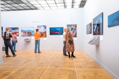 19 Ekim 2021, Moskova, Rusya: Koruma maskeli ziyaretçiler Altın Kaplumbağa sergisindeki vahşi yaşam fotoğraflarına bakıyorlar