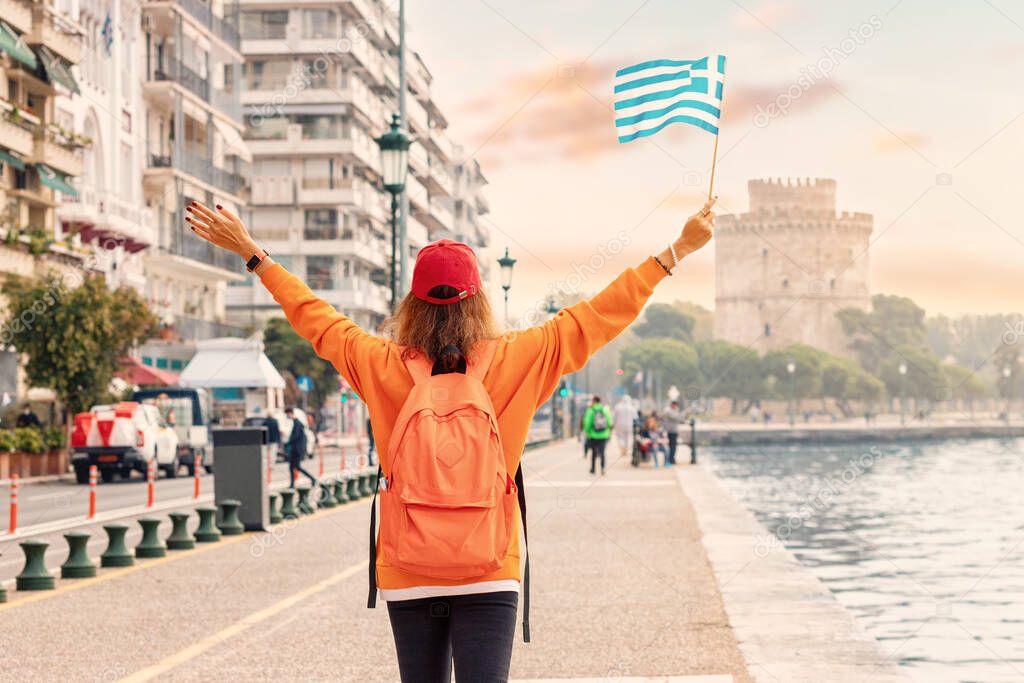 A student or immigrant girl with a Greek flag on the background of a White Tower in Thessaloniki. The concept of citizenship or learning Greek in university
