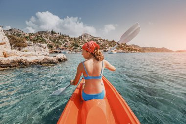 Mutlu kız, Kekova adası yakınlarındaki bir deniz kayığında Simena Şatosu ve Kaleucagiz köyü manzaralı kürek çekiyor. Açık hava eğlencesi ve keşfi. Bir yaşam tarzı olarak seyahat et.