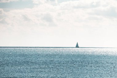 Uçsuz bucaksız mavi denizde tek başına yelken açan minimalist bir manzara.