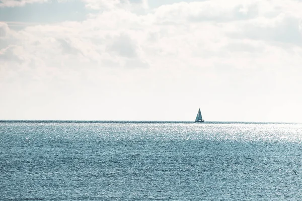 Uçsuz bucaksız mavi denizde tek başına yelken açan minimalist bir manzara.