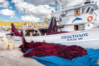 25 Ekim 2021, Neos Marmaras, Yunanistan: Rıhtımda kurutma ve onarım için bir balıkçı teknesi ve büyük bir ağ yığını