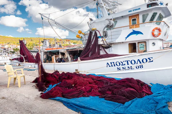 25 Ekim 2021, Neos Marmaras, Yunanistan: Rıhtımda kurutma ve onarım için bir balıkçı teknesi ve büyük bir ağ yığını