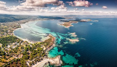 Yunanistan 'ın Vourvourou tatil köyündeki kumlu Karydi plajının insansız hava aracı görüntüsü. Sakin deniz suyunda farklı renklerde inanılmaz desenler var.