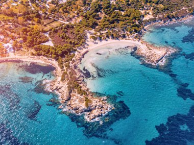 Türkuaz suyun çeşitli tonlarıyla cennet sahili havadan görünüyor. Sithonia, Halkidiki 'deki Vourvourou tatil köyündeki mercan resifleri ve tenha kumlu plajlar.