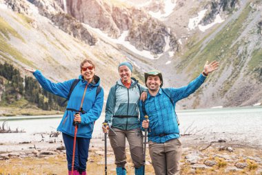 Bir grup arkadaş, Kuzey ülkesindeki bir doğa parkındaki cennet gibi bir dağ gölünün muhteşem manzarasının keyfini çıkarıyorlar.