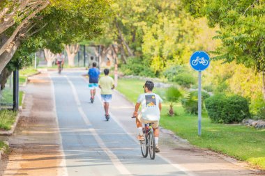 19 Mayıs 2022, Antalya, Türkiye: Bisikletçiler, boyalı kaldırım ve yol işaretleri olan bir parkta bisiklet yolu boyunca seyahat ediyorlar. Şehirdeki çevre dostu ulaşım altyapısı ve güvenlik