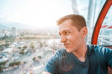 Depresyonda ve hayal kırıklığına uğramış genç bir adam lunaparkta dönme dolaba binerken selfie çekiyor. Yükseklik korkusu