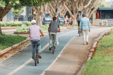 19 Mayıs 2022, Antalya, Türkiye: Bisikletçiler, boyalı kaldırım ve yol işaretleri olan bir parkta bisiklet yolu boyunca seyahat ediyorlar. Şehirdeki çevre dostu ulaşım altyapısı ve güvenlik